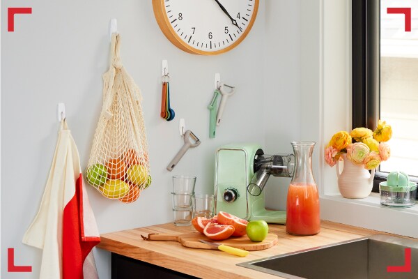 Cocina organizada donde se colgaron utensilios, frutas y mandil con Ganchos Command®.
